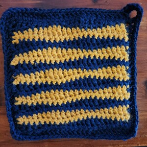 Op de afbeelding: Een blauwe en gouden gehaakte ovenwant met een gestreept patroon.