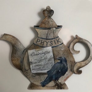 May include: A ceramic teapot painted with a raven, a handwritten recipe for "Crow's wing tea", and the word "Physik".