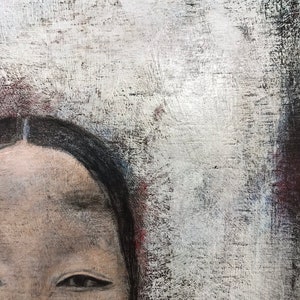 K&ouml;nnte beinhalten: Nahaufnahme eines Frauen Gesichts mit dunklen Haaren und braunen Augen. Der Hintergrund ist eine strukturierte wei&szlig;e und graue Leinwand.
