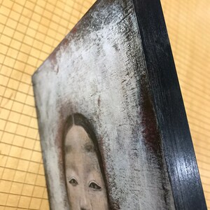K&ouml;nnte beinhalten: Eine Nahaufnahme eines Gem&auml;ldes mit dem Gesicht einer Frau. Die Frau hat dunkles Haar und tr&auml;gt ein wei&szlig;es Kleid. Das Gem&auml;lde ist auf einer Leinwand mit einem schwarzen Rahmen.
