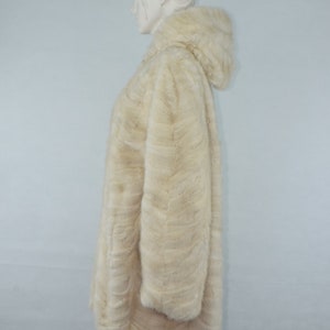 May include: A white fur coat with a hood. The coat is made of a soft, fluffy fur and has a long, flowing style.