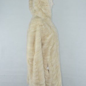 May include: A white fur hooded coat with a long, flowing design. The coat is made of soft, luxurious fur and has a classic, elegant style.