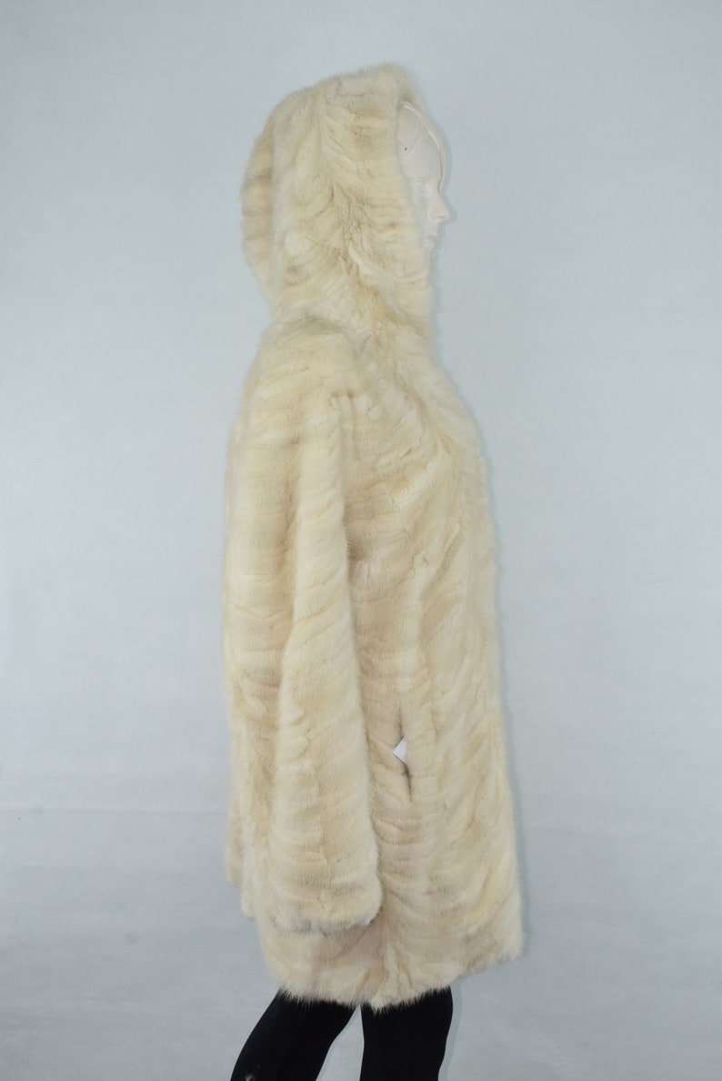 May include: A white fur hooded coat with a long, flowing design. The coat is made of soft, luxurious fur and has a classic, elegant style.
