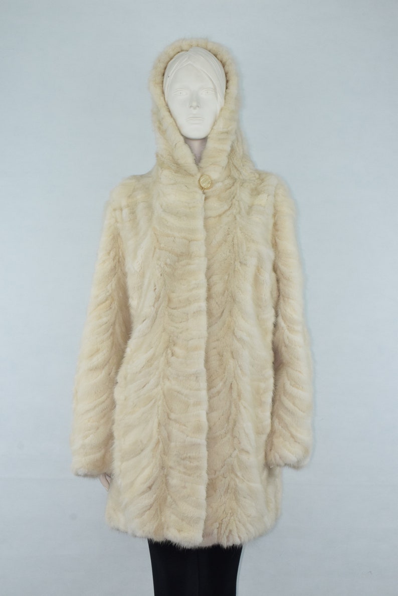 May include: A white fur coat with a hood. The coat has a button closure and a slightly flared silhouette.