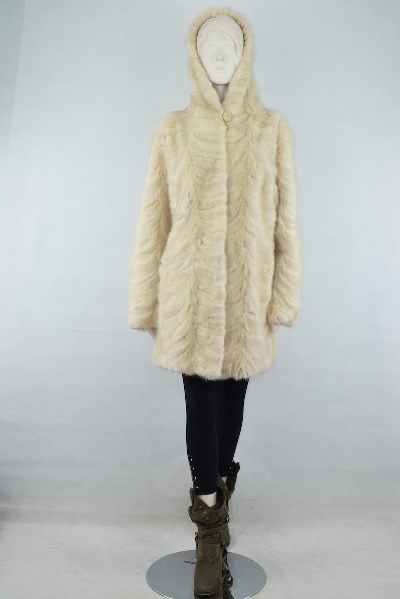May include: A white fur coat with a hood and a button closure. The coat is made of a soft, luxurious fur and has a sleek, modern design.