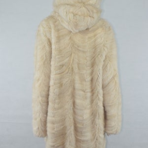 May include: A cream-colored fur coat with a hood. The coat is made of a soft, plush fur and has a long, flowing style.