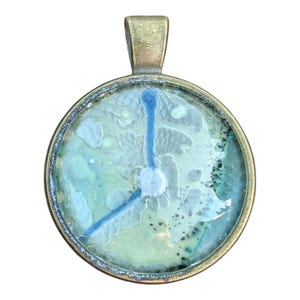 May include: A round pendant necklace with a blue and green abstract design inside a bronze frame.