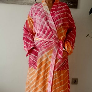 May include: A long, pink and orange tie-dye robe with a sash tie. The robe has two pockets on the front.
