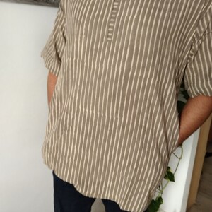 May include: A brown and white striped shirt with a short sleeve and a button-up collar.