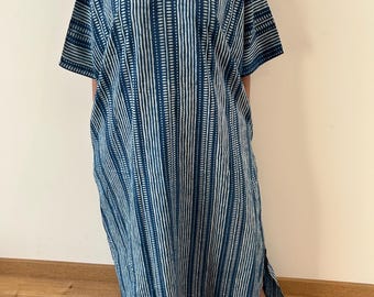 Puede incluir: Un vestido tipo caftán largo hasta el suelo con escote en V profundo y mangas cortas. La prenda presenta rayas verticales en tonos azul oscuro y blanco, incorporando un diseño de textura repetitiva similar a guiones en toda la tela.