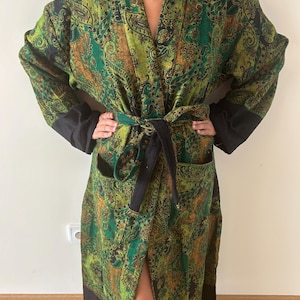 Può includere: Accappatoio verde a fantasia paisley con finiture nere e cintura abbinata. L'accappatoio presenta un design vibrante con sfumature di verde, marrone e nero. L'accappatoio ha maniche lunghe e tasche.