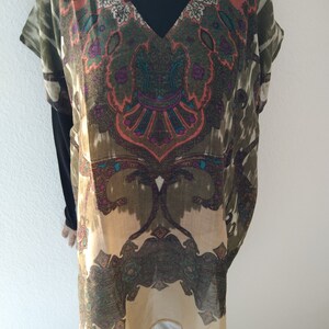 May include: A beige and green tunic with a paisley print. The tunic has a V-neck and short sleeves.
