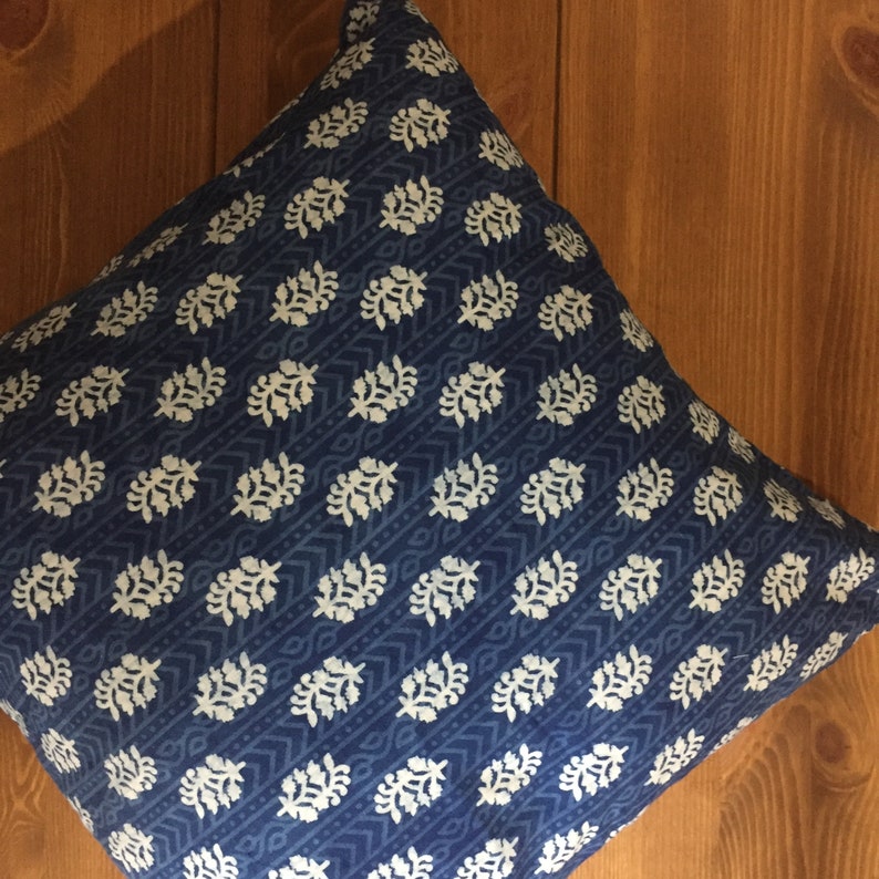 May include: A blue and white patterned throw pillow with a floral design. The pillow is made of cotton and has a soft, comfortable feel.