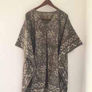 May include: A brown and white patterned cotton kaftan with a V-neck and short sleeves. The kaftan has a tie at the waist and a geometric pattern around the hem.