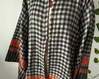 May include: A black and white gingham button-up shirt with a long, flowing silhouette. The shirt has a colorful embroidered trim around the edges.