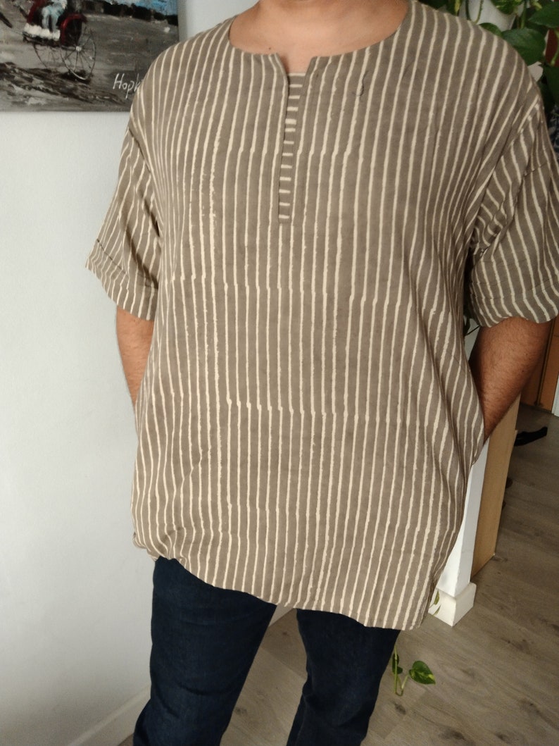 May include: A brown and white striped shirt with a short sleeve and a v-neck. The shirt has a button closure at the neck.