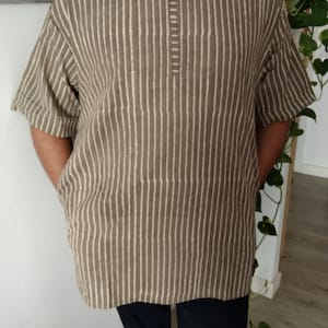 May include: A brown and white striped short-sleeved shirt with a round neckline and a button closure at the neck.