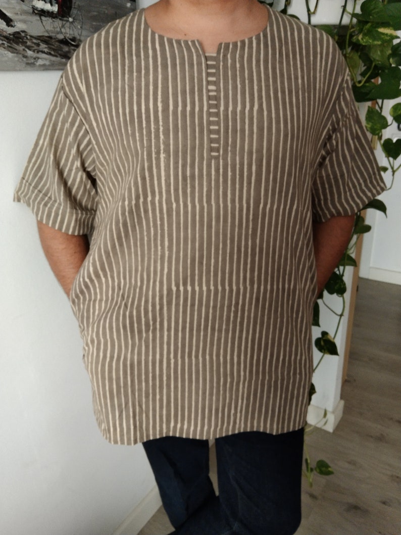 May include: A brown and white striped short-sleeved shirt with a round neckline and a button closure at the neck.