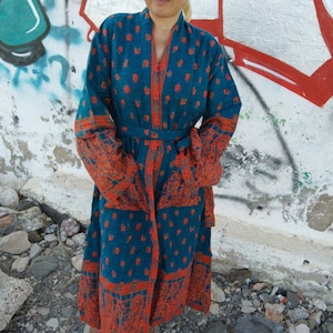 May include: A long teal blue robe with a red and white paisley pattern. The robe has a tie belt and long sleeves.