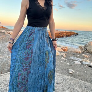 May include: A blue maxi skirt with a floral print. The skirt has a drawstring waist and a flowing silhouette.