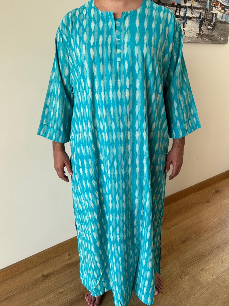 May include: A turquoise blue long-sleeved shirt with a white and turquoise pattern. The shirt has a button-up collar and a relaxed fit.