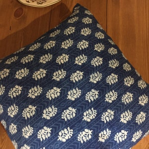 May include: A blue throw pillow with a white floral pattern. The pillow is made of a soft, cotton fabric and is perfect for adding a touch of style to any room.
