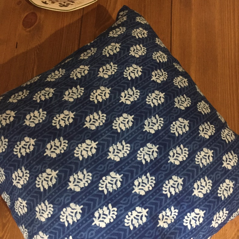 May include: A blue throw pillow with a white floral pattern. The pillow is made of a soft, cotton fabric and is perfect for adding a touch of style to any room.