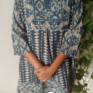 May include: A blue and beige patterned tunic with a V-neck and three-quarter sleeves.