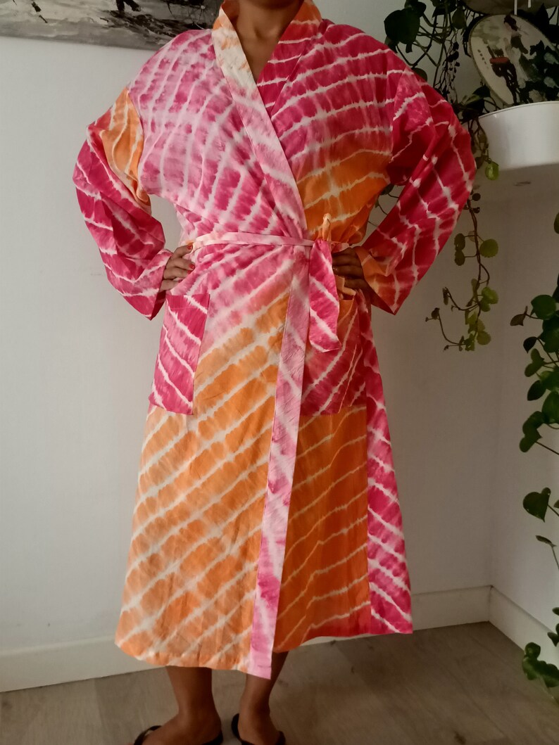 May include: A pink and orange tie-dye robe with a long sleeve and a sash tie.