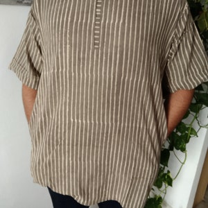 May include: A brown and white striped short-sleeved shirt with a round neckline and a button closure at the neck.
