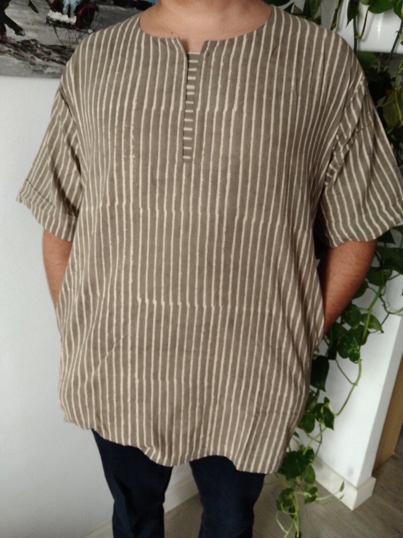 May include: A brown and white striped short-sleeved shirt with a round neckline and a button closure at the neck.