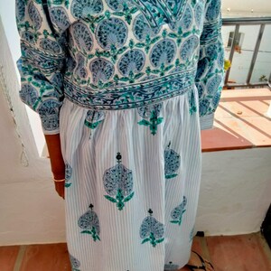 May include: A long-sleeved blue and white dress with a floral print. The dress has a V-neckline and a gathered waist. The fabric is lightweight and has a soft texture.