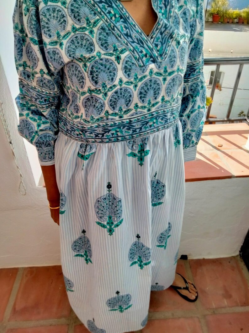 May include: A long-sleeved blue and white dress with a floral print. The dress has a V-neckline and a gathered waist. The fabric is lightweight and has a soft texture.