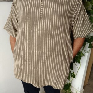 May include: A brown and white striped short-sleeved shirt with a V-neck and a button closure.