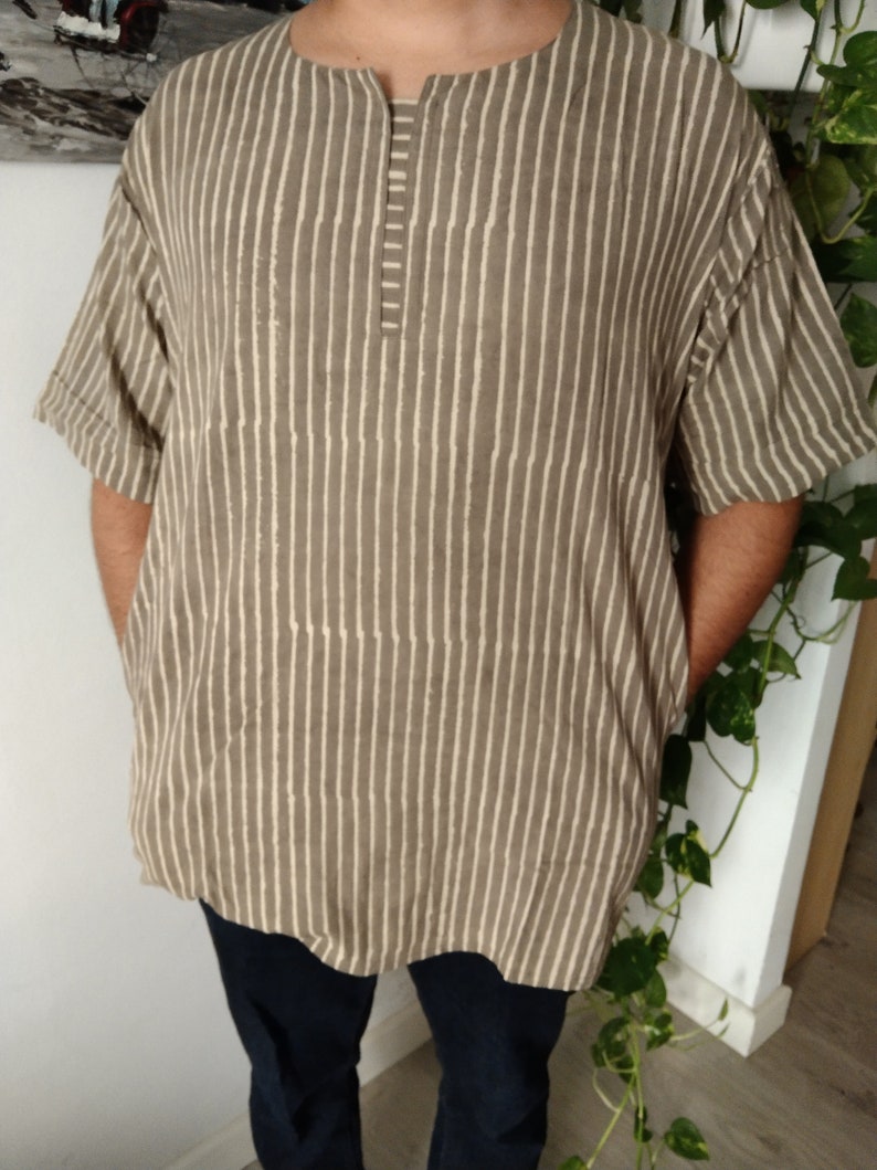 May include: A brown and white striped short-sleeved shirt with a V-neck and a button closure.