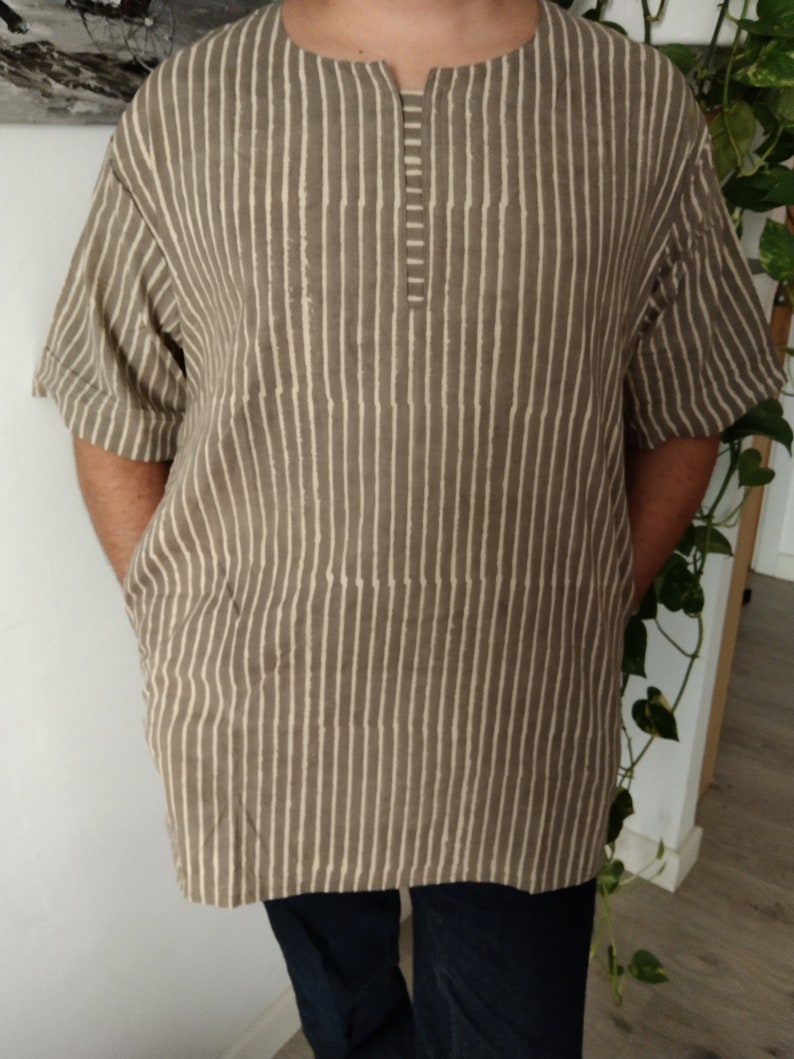 May include: A brown and white striped shirt with a short sleeve and a v-neck.