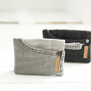 Puede incluir: Dos bolsas de mezclilla con una etiqueta de cuero marrón que dice "remarkable". La bolsa de la izquierda es gris claro y la bolsa de la derecha es negra.