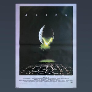 Può includere: Un poster del film "Alien". Il titolo è in alto, con un'immagine di un uovo con luce verde. La parte inferiore del poster mostra una superficie scura e strutturata. Sono presenti anche i crediti.