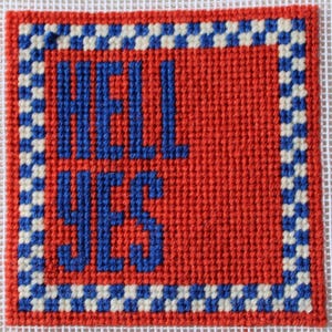 Può includere: Una tela quadrata per ricamo a mezzo punto con il testo HELL YES cucito in filo blu su uno sfondo rosso a tinta unita. Il design è racchiuso da un bordo a scacchi blu e bianchi, il tutto realizzato su una base di tessuto a rete bianca.