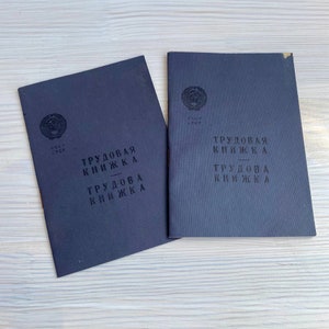 May include: Two black workbooks with the text "TRUDOVAYA KNIZHKA" printed on the front. The workbooks have a red star and the text "SSSR SSSR" printed on the front.
