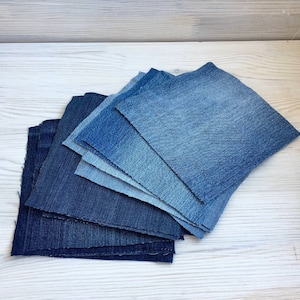 Peut inclure: Un empilement de carrés de tissu en jean dans différentes nuances de bleu, du foncé au clair.