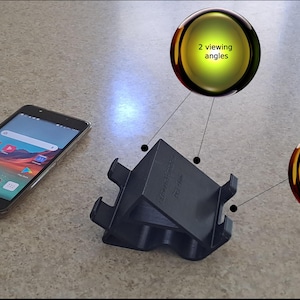 Puede incluir: Soporte de teléfono negro con dos ángulos de visión. El soporte tiene recortes para un fácil acceso a la pantalla y al cable.