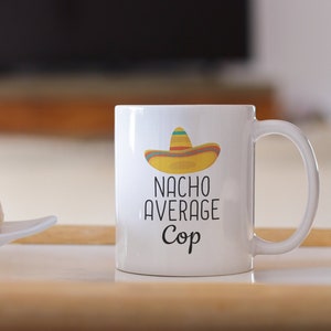 May include: White ceramic mug with a black and white graphic of a sombrero and the text "Nacho Average Cop".