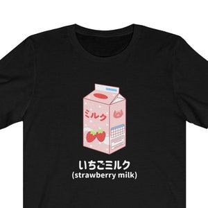 May include: Black t-shirt with a cartoon illustration of a pink carton of strawberry milk. The carton has the Japanese word "ミルク" (milk) and the text "いちごミルク (strawberry milk)".