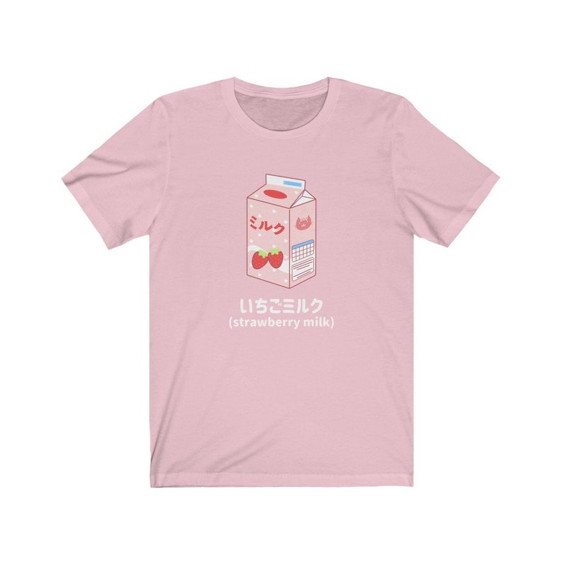 May include: Pink t-shirt with a cartoon illustration of a carton of strawberry milk. The carton is labeled "ミルク" (milk) and "いちごミルク" (strawberry milk).