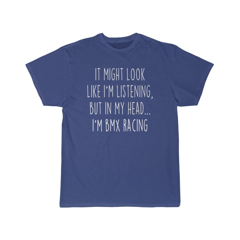 Op de afbeelding: Een blauw t-shirt met witte tekst die "IT MIGHT LOOK LIKE I'M LISTENING, BUT IN MY HEAD... I'M BMX RACING" zegt.