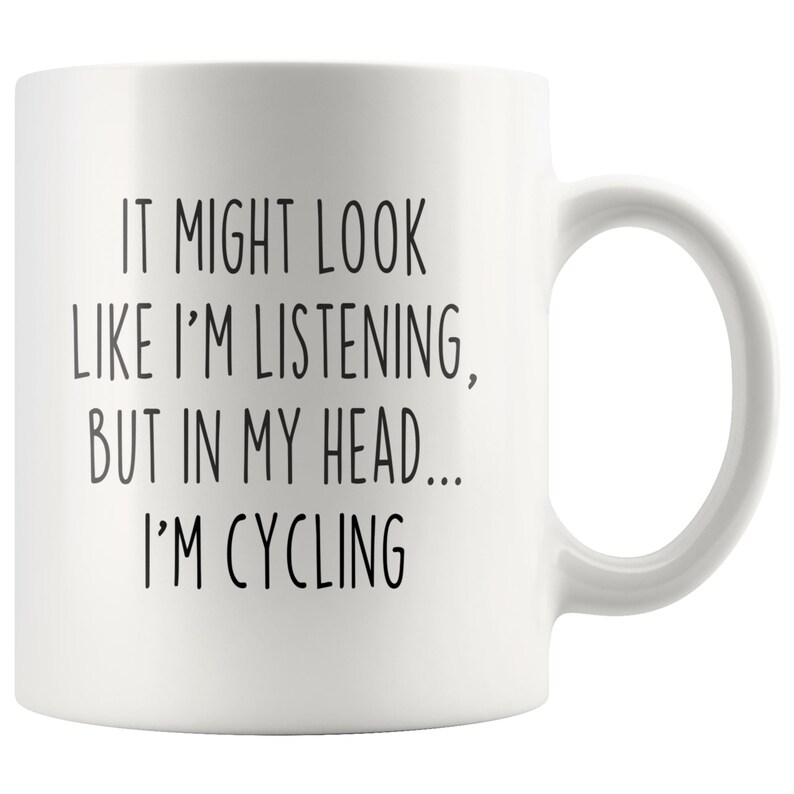 May include: White ceramic coffee mug with black text that reads "It might look like I'm listening, but in my head... I'm cycling."