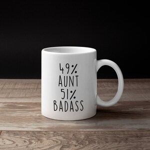 Puede incluir: Taza de cer&aacute;mica blanca con texto negro que dice "49% T&iacute;a 51% Badass".