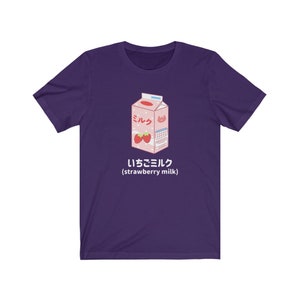 May include: Purple t-shirt with a cartoon illustration of a carton of strawberry milk. The carton is pink and white with the Japanese word for milk, "ミルク", and the text "いちごミルク (strawberry milk)".