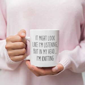 May include: White ceramic mug with black text that reads "It might look like I'm listening, but in my head... I'm knitting".